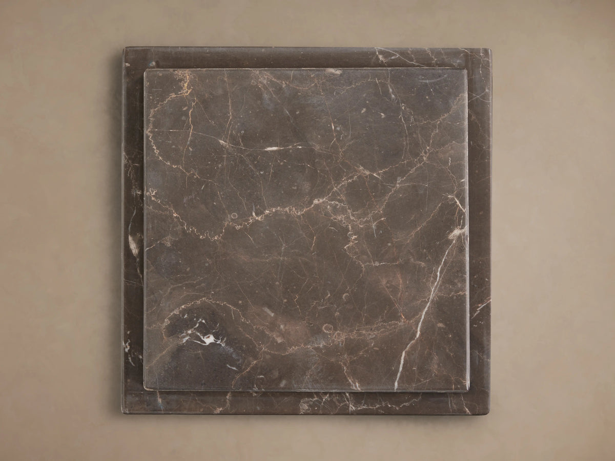 Three Marmont Pedestals of varying heights, dark gray natural marble with white veining, on a wood floor.