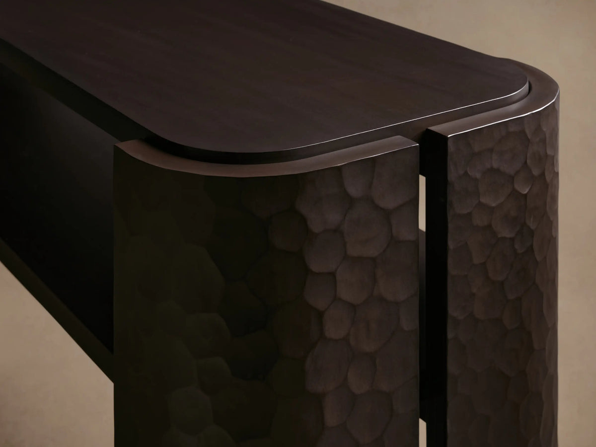 Dark brown Chiseled Console Table with rectangular top and lower shelf. Features hand-carved textured legs curving around the sides.