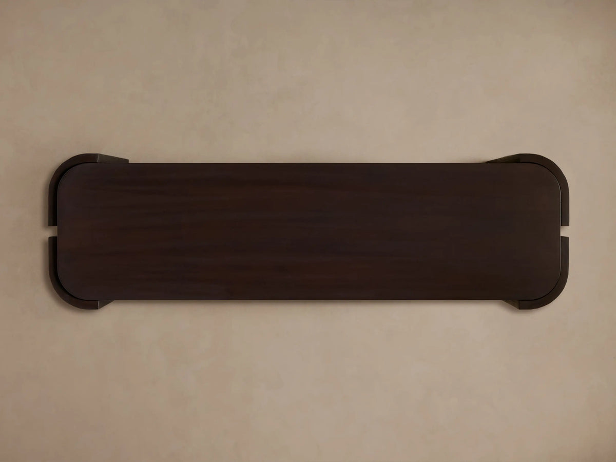 Dark brown Chiseled Console Table, front view. Hand-carved legs with textured finish wrap around two dark wood shelves.