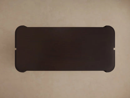 Close-up of a dark brown Chiseled Coffee Table, showing its curved, hand-carved chiseled textured side and smooth top.
