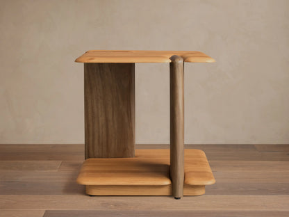 Front view of a light brown wooden side table, featuring a flat top and base with rounded edges, supported by a wide slab and a rounded leg.