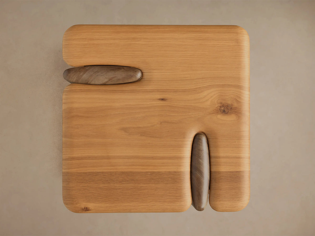 Close-up of the light brown wooden piece's top surface and curved leg, showing smooth rounded edges and natural wood grain.