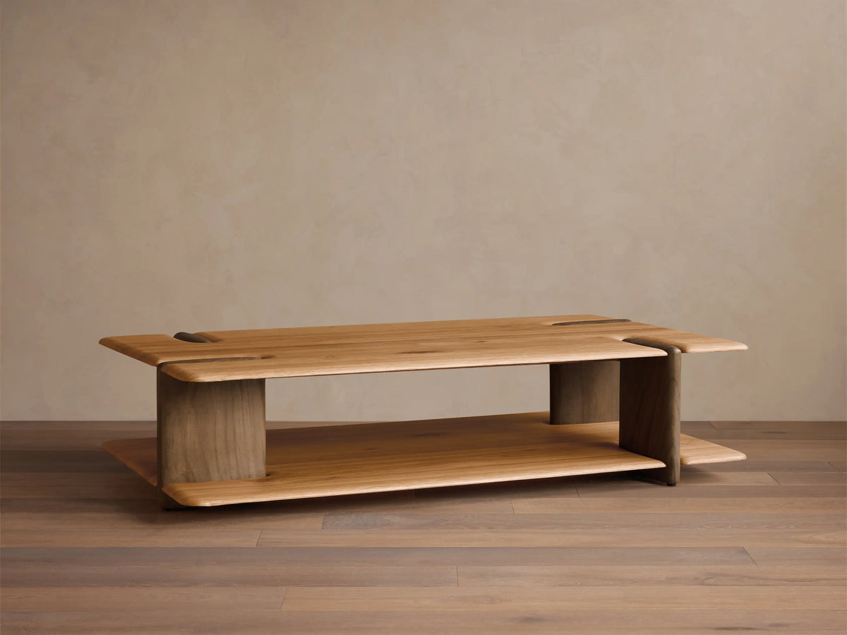Front view of a natural light wood coffee table with a sculpted, rectangular top featuring organic cutouts, supported by curved legs and a lower shelf.