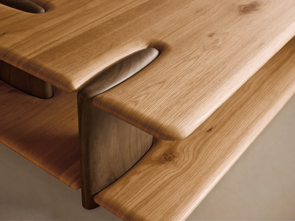 Front view of a light brown wooden coffee table with a rectangular top, lower shelf, integrated curved supports, and sculpted groove details.