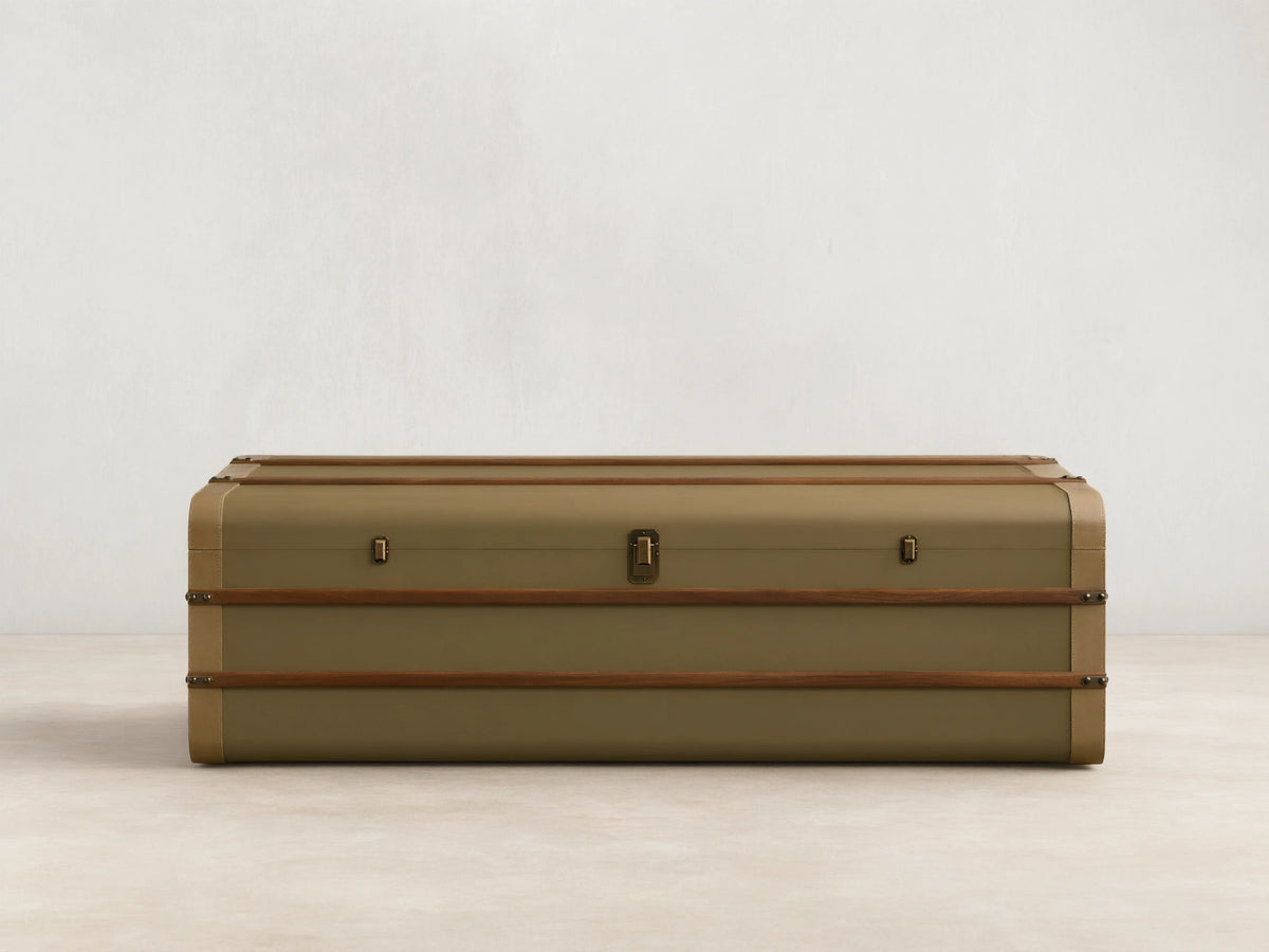 Front view of the olive Oberlin Storage Coffee Table, a trunk-style table with beige leather trim, a brass-tone lock, and wooden bands.