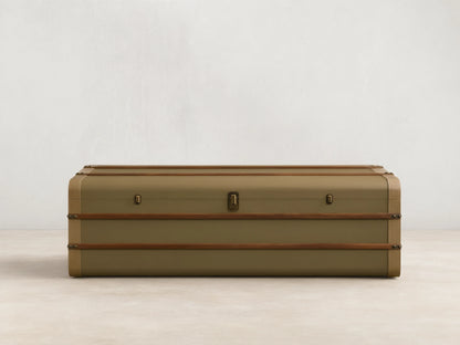 Front view of the olive Oberlin Storage Coffee Table, a trunk-style table with beige leather trim, a brass-tone lock, and wooden bands.