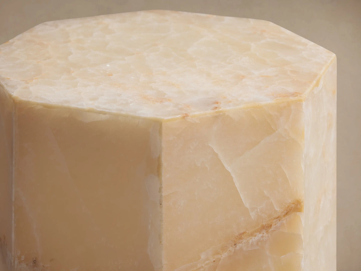 Odelia Onyx Stool: Octagonal column of honed ivory and beige onyx with natural veining, on a wood floor.