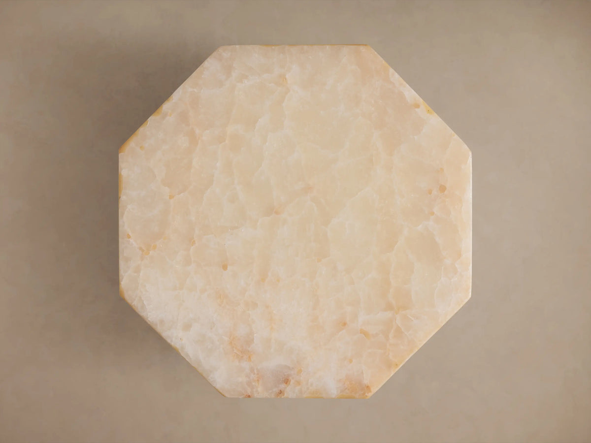 Close-up of Odelia Onyx Stool, an octagonal ivory and beige honed solid onyx stool with natural color variations.