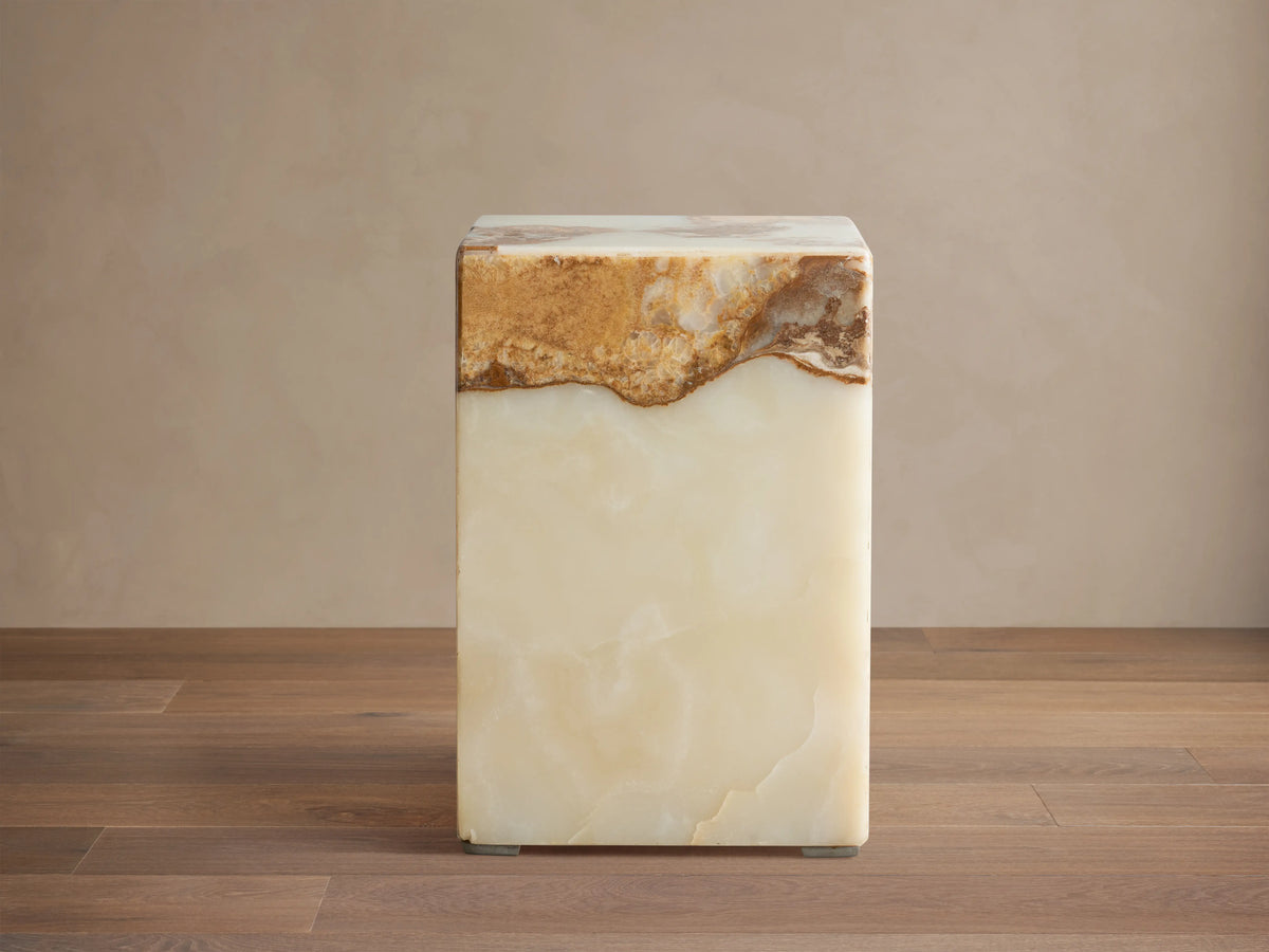 Rust Onyx Stool: rectangular block with a prominent horizontal band of rustic brown/gold/red onyx atop smooth ivory/green onyx, on a wood floor.