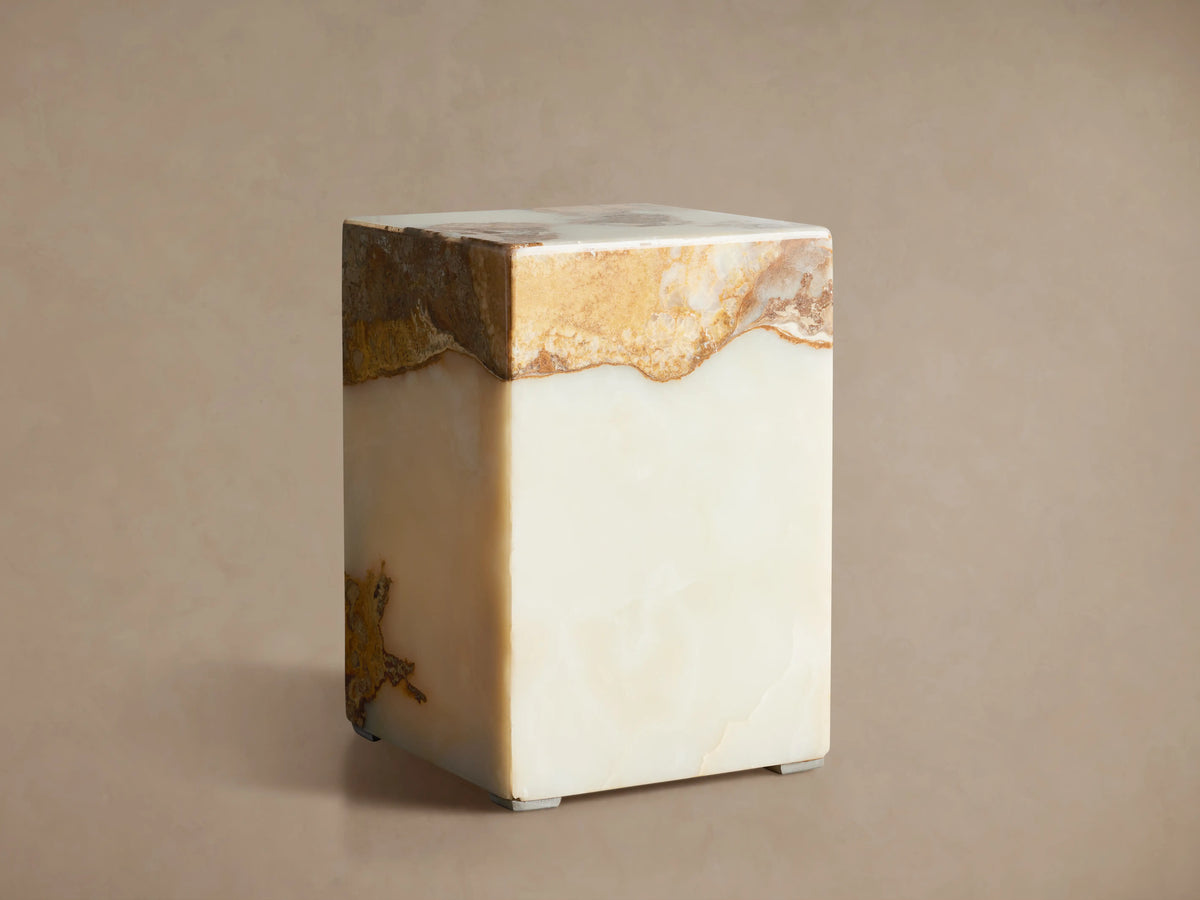 Rust Onyx Stool: rectangular block with a prominent horizontal band of rustic brown/gold/red onyx atop smooth ivory/green onyx, on a wood floor.