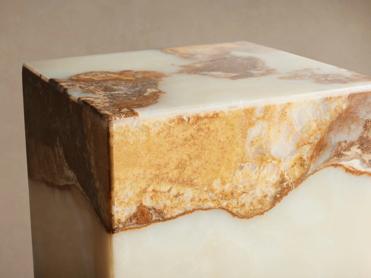 Rust Onyx Stool, a rectangular block of ivory onyx with a wavy top section featuring rustic brown, gold, and green tones.