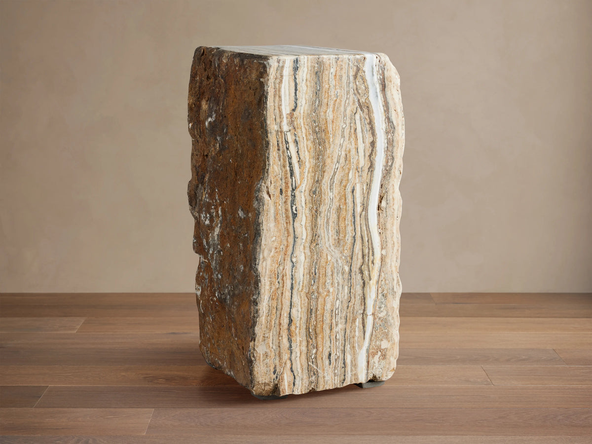 Solid Onyx Stool with vertical raw edges, showcasing natural brown and beige striations, sits on a wooden floor.
