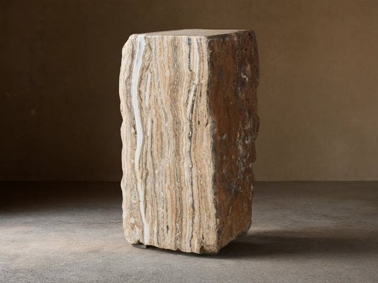 Solid Onyx Stool with vertical raw edges, showcasing natural brown and beige striations, sits on a wooden floor.