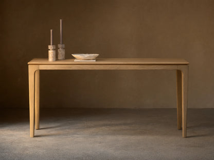 Long, narrow Park Console Table in light oak, with slender, curved legs. Two candles and a decorative bowl sit on top.