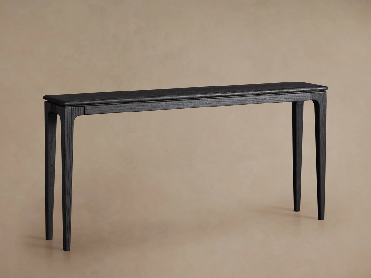 Park Console Table made of ash wood with a rich ebony finish, featuring minimalist design and tapered legs on a beige background.