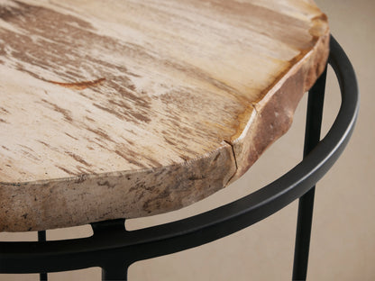 Front view of a round side table with a petrified wood slab top and a black metal base with an X-shaped support.