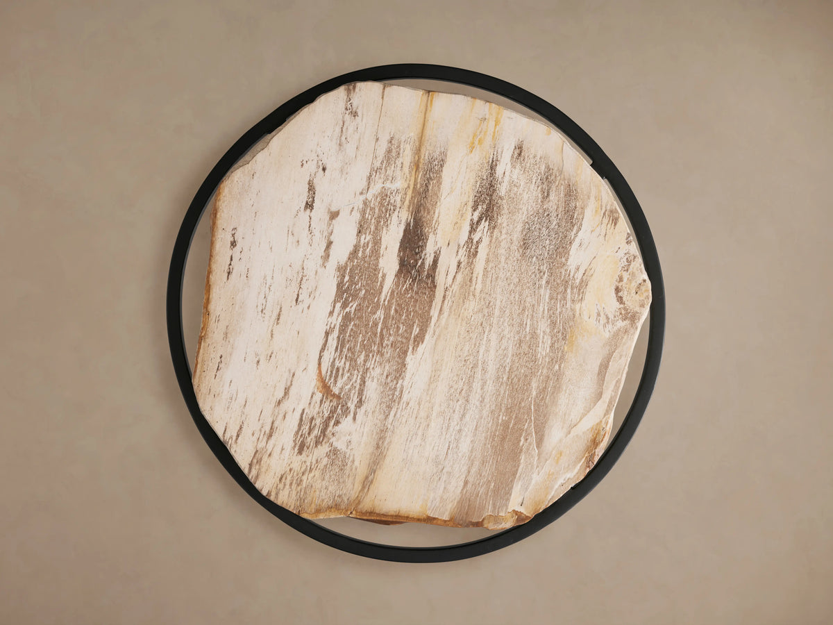 Close-up of a light brown natural wood round side table with a live edge and visible grain, on a black metal frame.