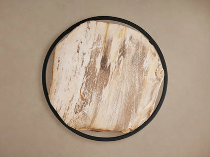 Close-up of a light brown natural wood round side table with a live edge and visible grain, on a black metal frame.