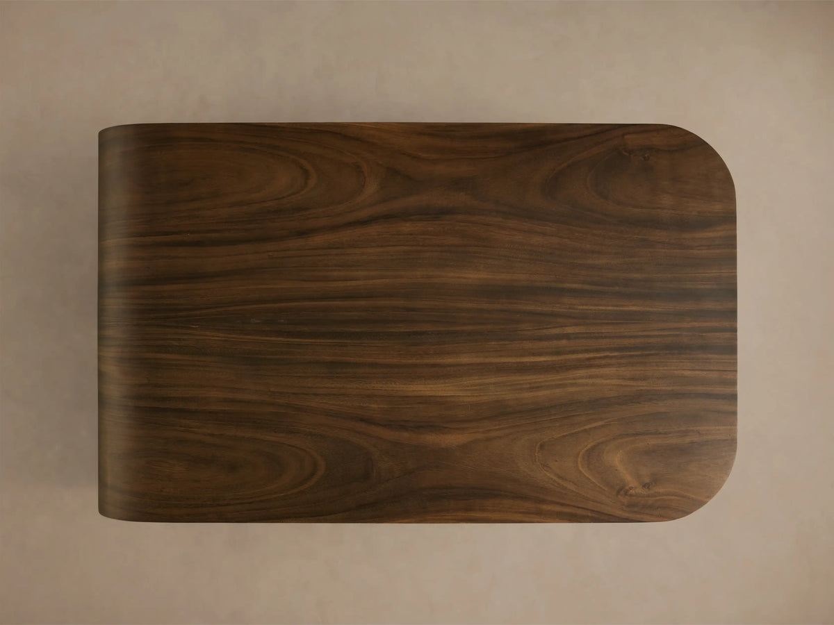 Overhead view of a dark brown wooden panel with natural grain patterns, a rounded right corner, and a gently curved left edge.