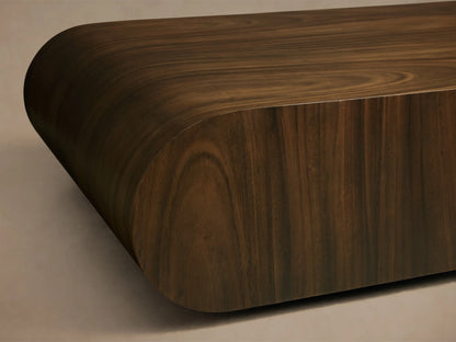 Close-up of a dark brown wood surface with visible grain, showing a smoothly rounded edge and curved profile.