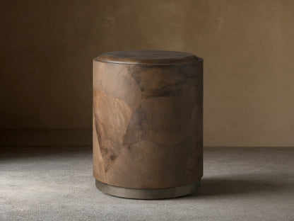 Polanco Round Plinth End Table, dark natural wood with oyster-cut fragments, cylindrical shape, on a weathered metal base.