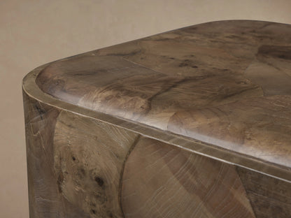 Polanco Plinth End Table, cube-shaped, made of varied brown oyster-cut wood fragments with rounded edges, on a dark weathered steel base.