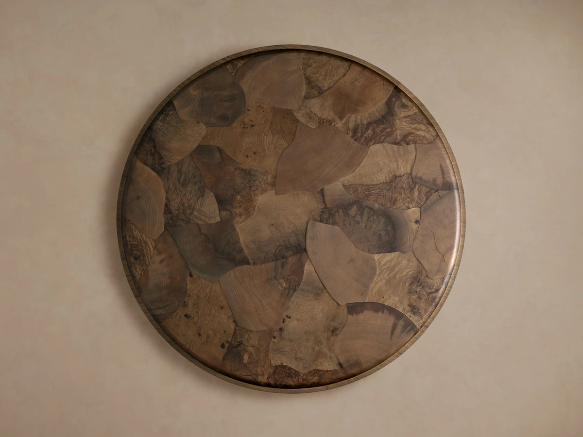 Polanco Round Plinth Coffee Table with oyster-cut ash fragments creating a mosaic pattern. Tabletop has a smooth finish with varied wood tones.