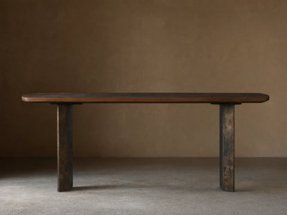 Polanco Console Table featuring an elongated wooden top with visible grain, supported by two steel legs with a weathered patina finish.
