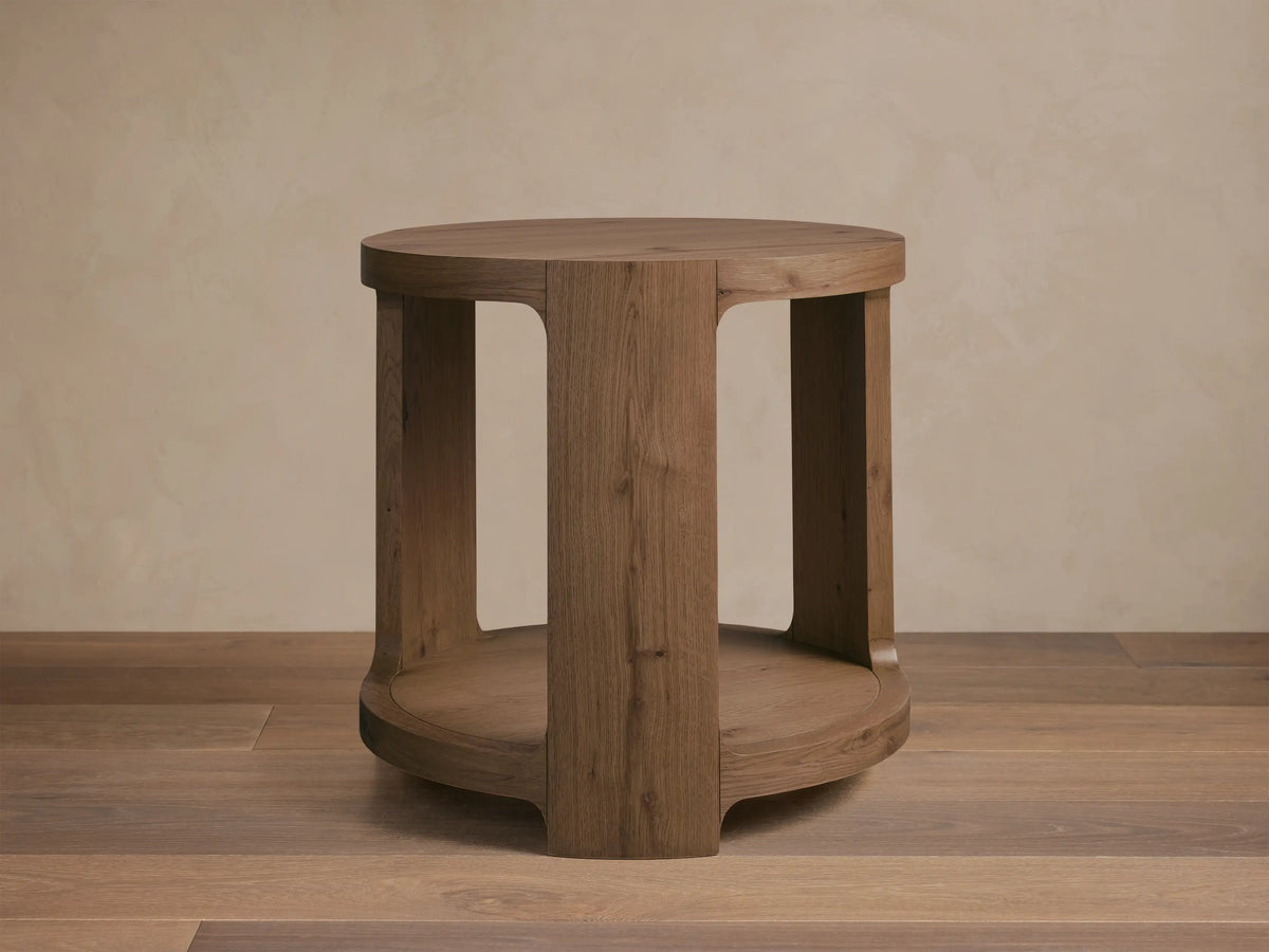 Front view of the round natural oak Redding End Table, featuring an open base and lower storage shelf with visible wood grain.