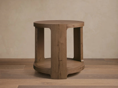 Front view of the round natural oak Redding End Table, featuring an open base and lower storage shelf with visible wood grain.