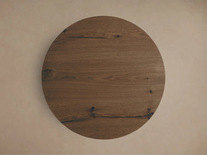 Close-up, angled view of a round brown Redding End Table showing visible wood grain, knots, and an arched cut-out in the base.