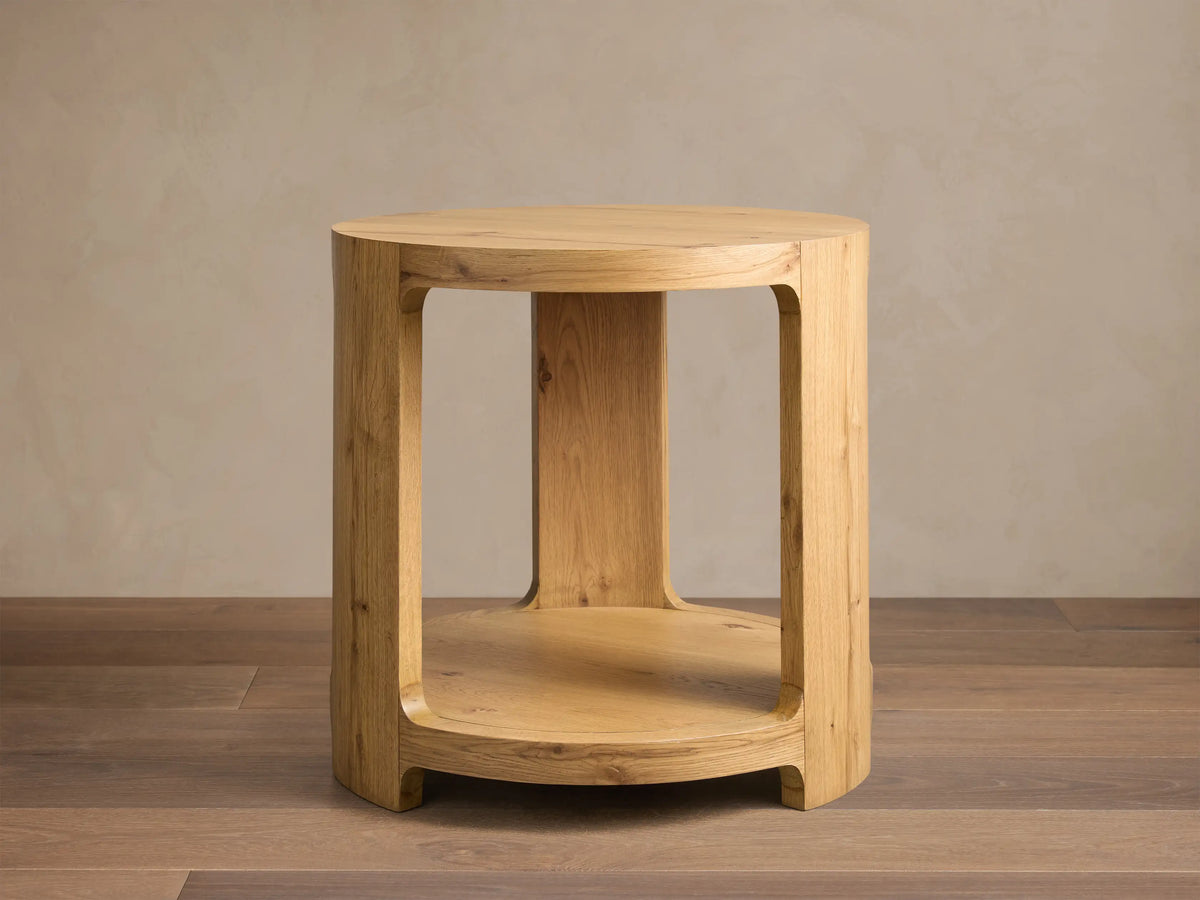 Front view of the natural white oak Redding End Table, featuring a round top and lower shelf supported by curved, thick legs.
