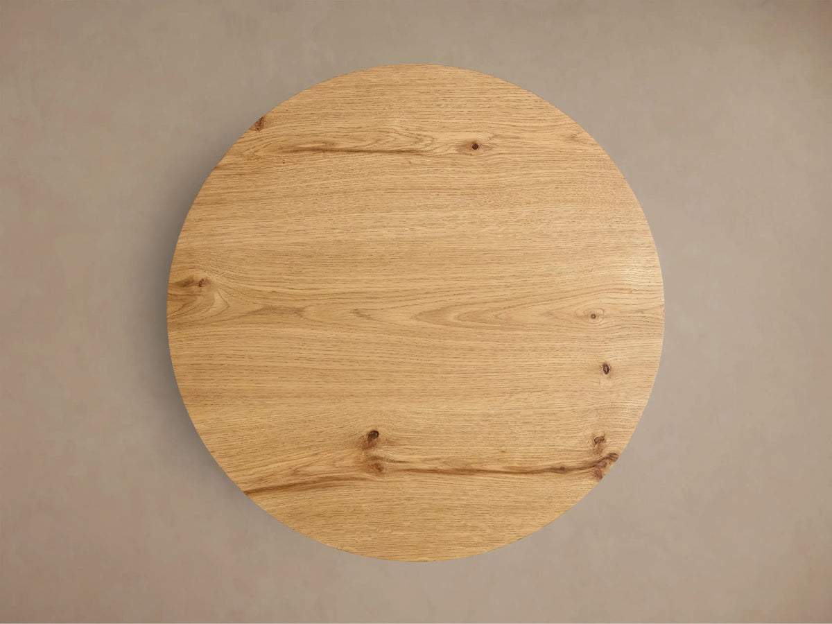 Front view of the natural white oak Redding End Table, featuring a round top and lower shelf supported by curved, thick legs.