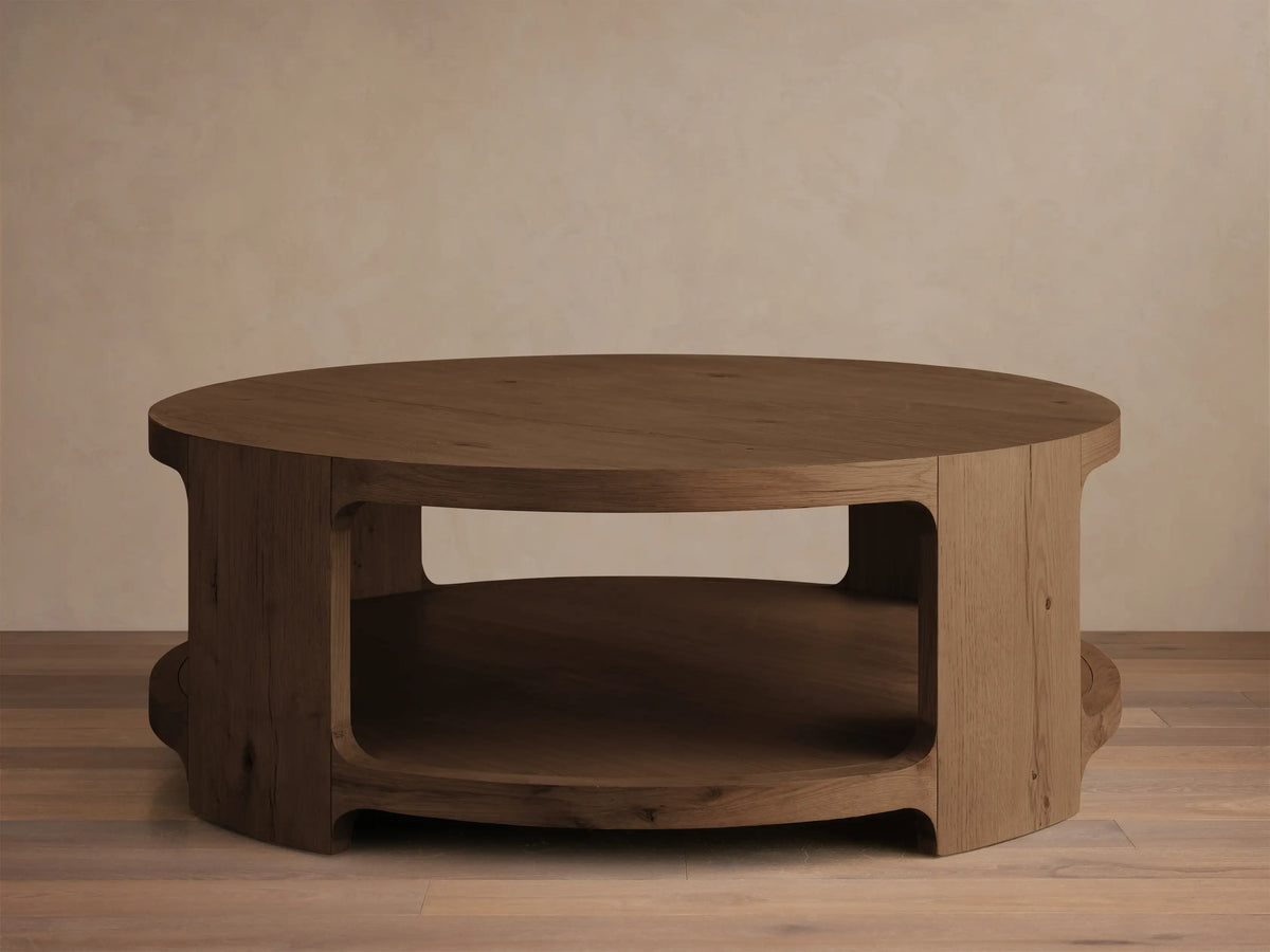 Angled front view of the medium brown wood Redding Round Coffee Table, featuring a thick round top and a built-in lower shelf.