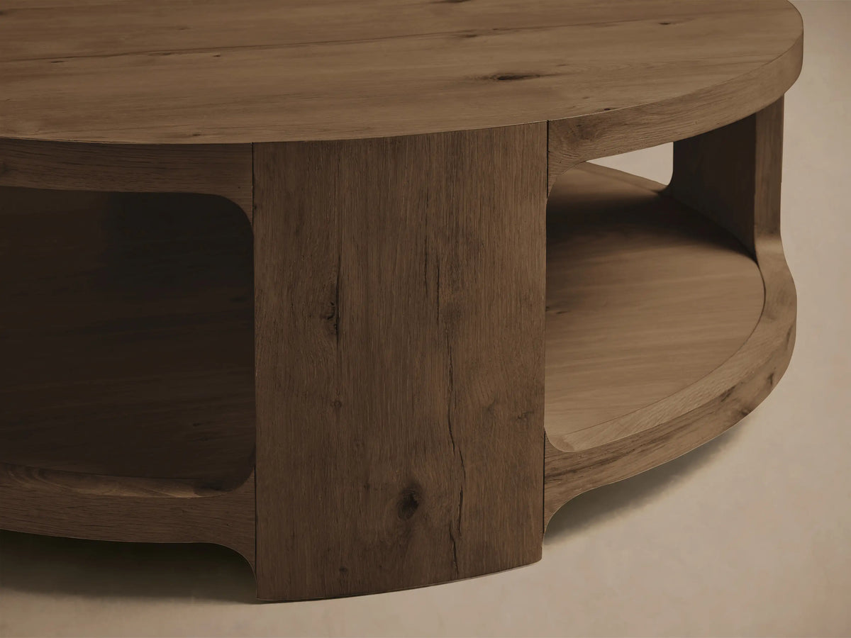 Close-up of the brown Redding Round Coffee Table, an angled view showing its round top and lower shelf crafted from knotty white oak.
