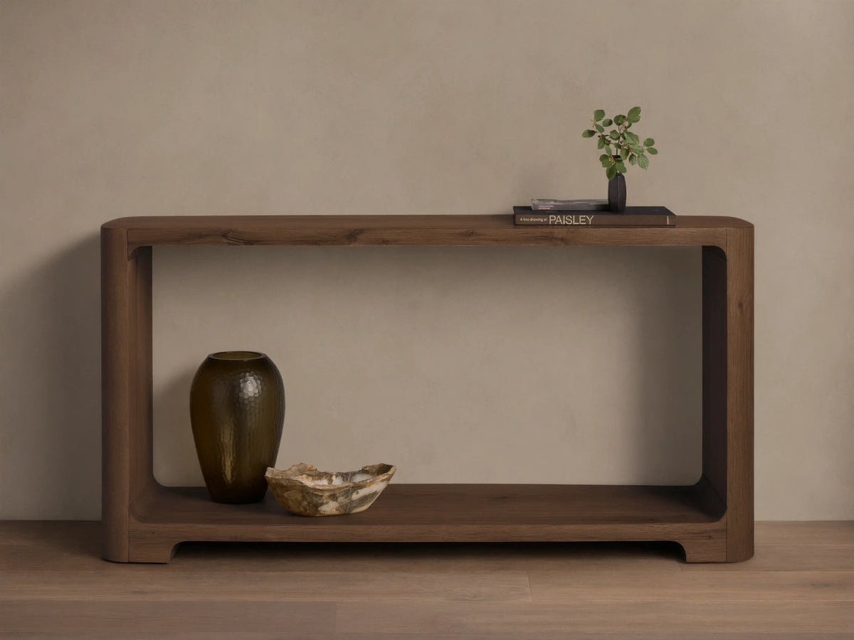 Front view of the dark brown Redding Console Table with a lower shelf and rounded edges, styled with vases and books.