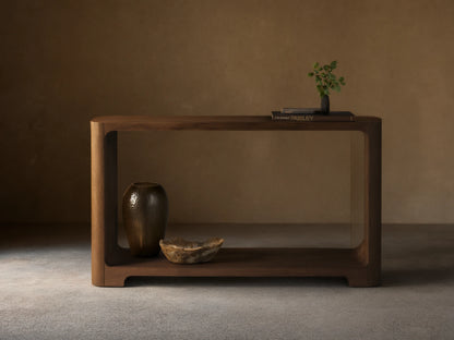 Front view of the dark brown Redding Console Table with a lower shelf and rounded edges, styled with vases and books.