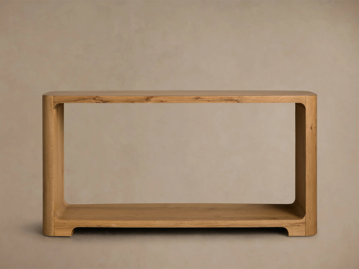 Front view of the natural wood Redding Console Table, featuring a curved design, upper surface, and lower shelf with decorative items.