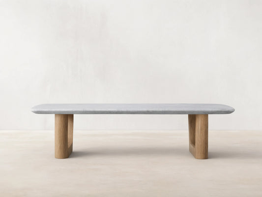 Front view of the Saint Germain Stone Coffee Table with Rennes Base, a light gray marble top with rounded edges and light brown oak legs.