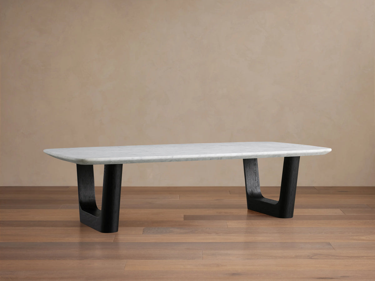 Saint Germain Stone Coffee Table with Carrara marble top, featuring a rectangular shape and black base, on wooden floor.