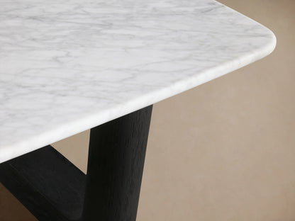 Saint Germain Stone Coffee Table with a rectangular Carrara marble top and ebony-finished wooden base, set against a wooden floor.