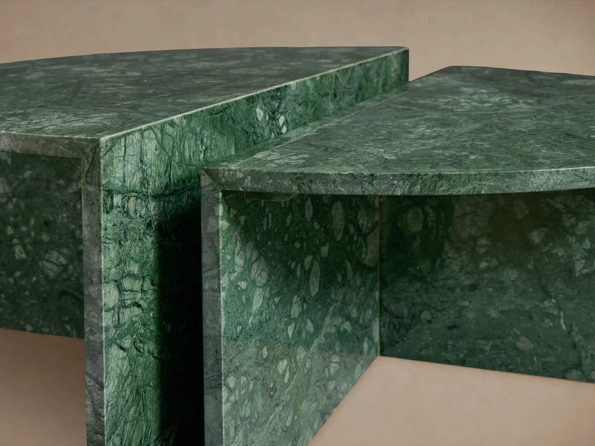 Riggs Coffee Table with a round design, rich green marble texture, on a wooden floor against a beige background.