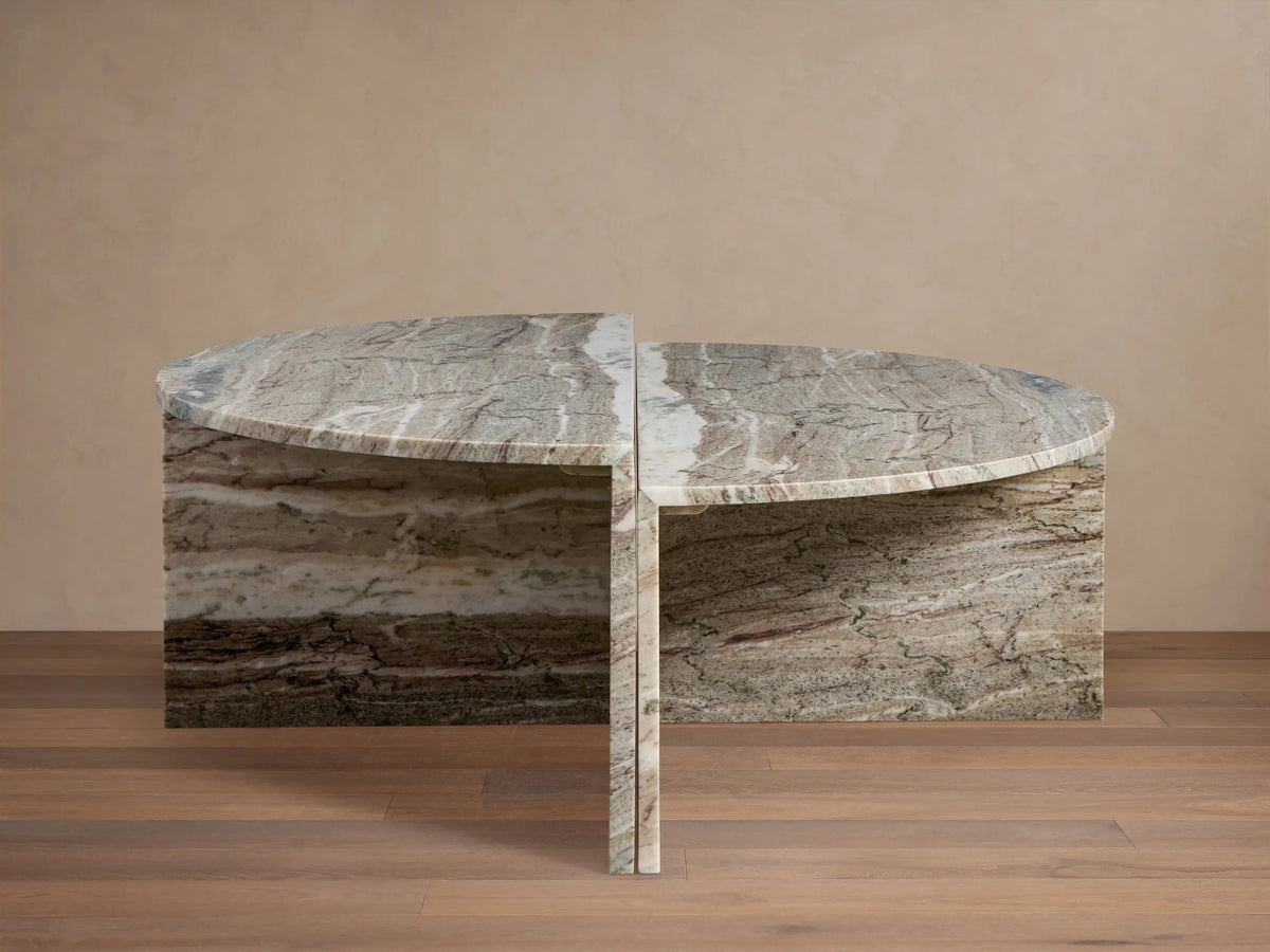 Riggs Coffee Table with semi-circular marble top, visible natural veins, and matching base on wooden floor, beige background.
