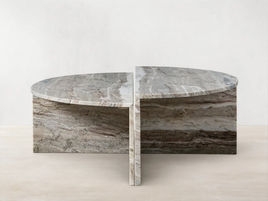 Riggs Coffee Table with semi-circular marble top, visible natural veins, and matching base on wooden floor, beige background.
