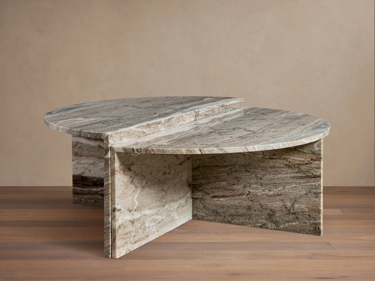Riggs Coffee Table in a semi-circular shape with a marbled stone finish, featuring a layered design and resting on a wooden floor.