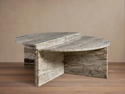 Riggs Coffee Table in a semi-circular shape with a marbled stone finish, featuring a layered design and resting on a wooden floor.