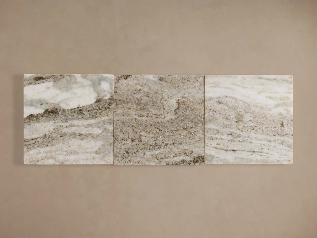Three rectangular stone slabs with a marbled pattern in shades of cream and gray, aligned horizontally against a beige background.