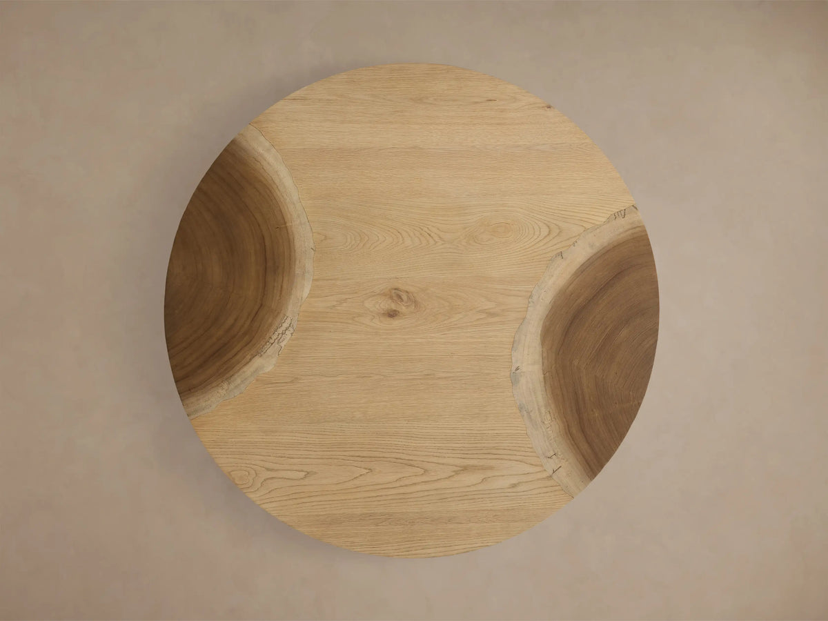 Close-up of a light brown, curved solid wood table, featuring natural wood grain patterns and a smooth finish.