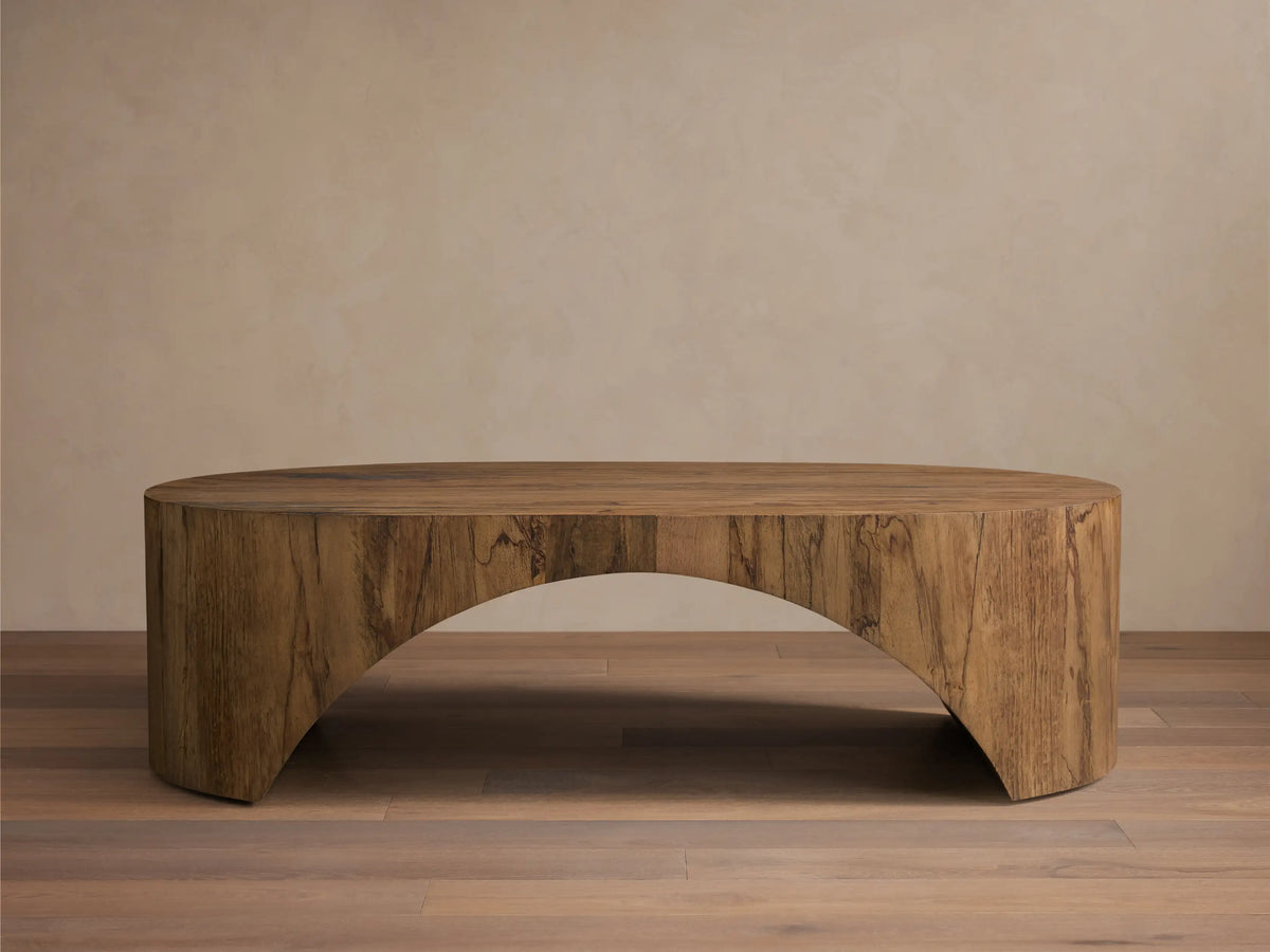 Front view of the aged brown San Rafael Coffee Table. This oval coffee table features a thick top and gracefully curved, arched legs.