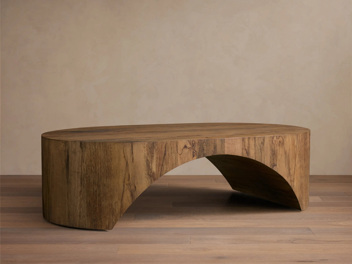 Front view of the aged brown San Rafael Coffee Table. This oval coffee table features a thick top and gracefully curved, arched legs.